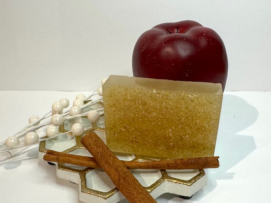 Bar of soap with an apple, cinnamon stick, and decorative elements on a white background