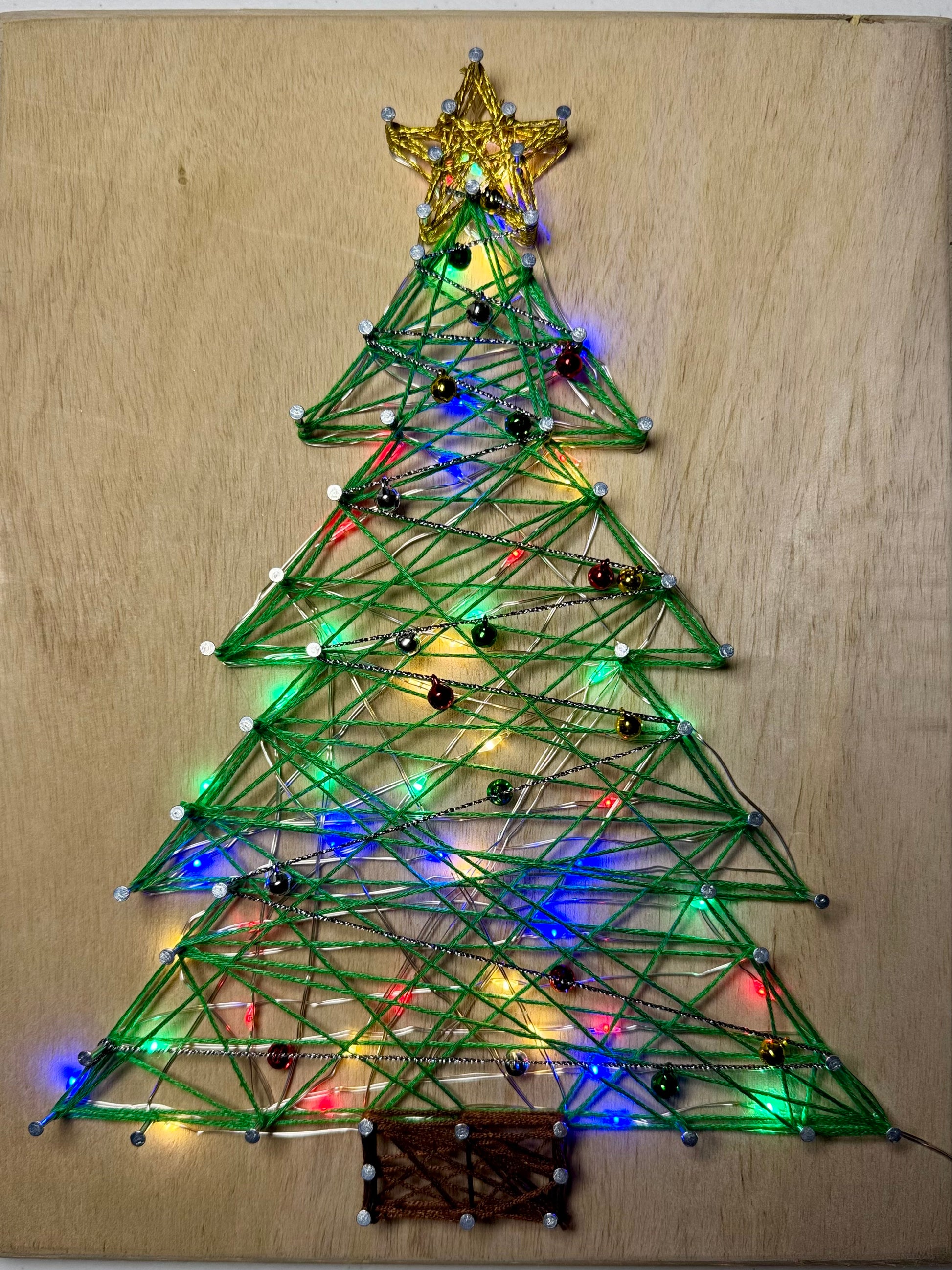 String art Christmas tree with lights on a wooden board
