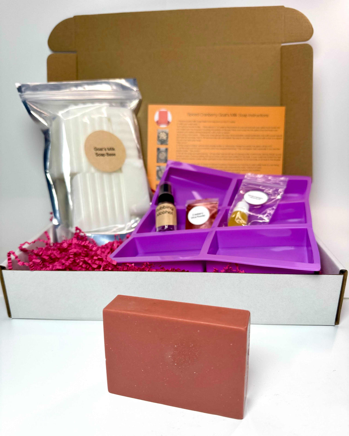 Spiced Cranberry Soap Making Kit with a reddish-brown soap bar, goat’s milk soap base, fragrance supplies and purple mold