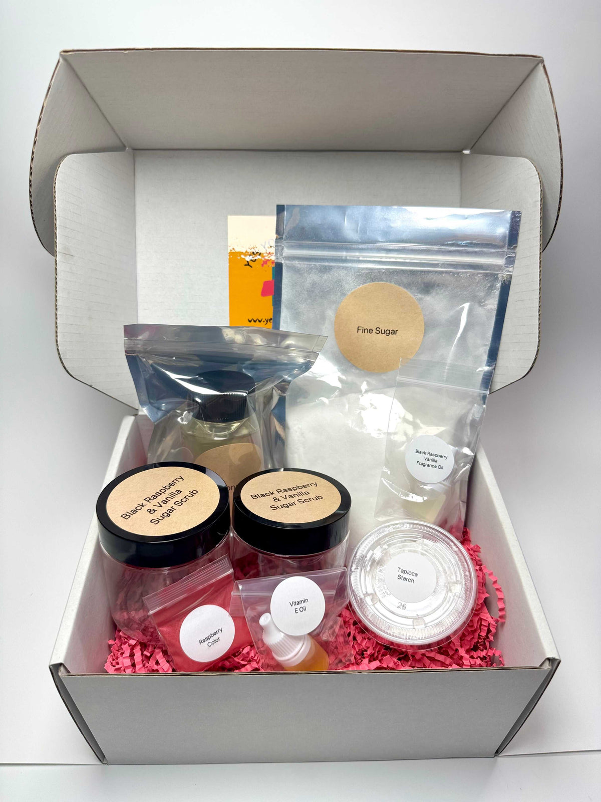 Black Raspberry & Vanilla Sugar Scrub making kit with clear ingredient bags, two jars, oil bottles and a mixing container.
