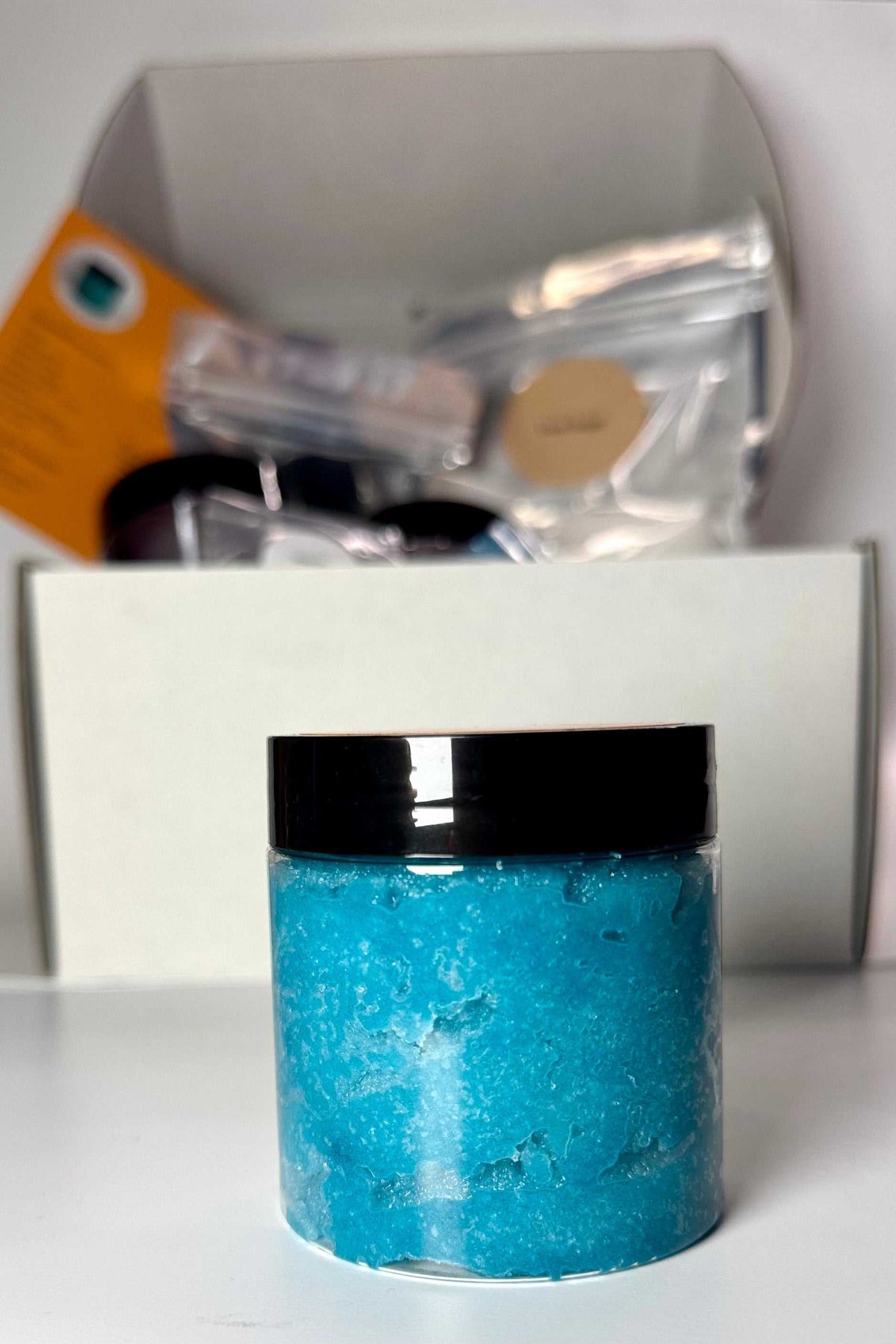 Blue Raspberry Sugar Scrub in a clear jar, showing bright turquoise-blue grainy scrub beneath a black lid